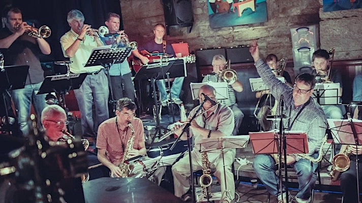 Jazz band performing on stage with instruments and musicians.
